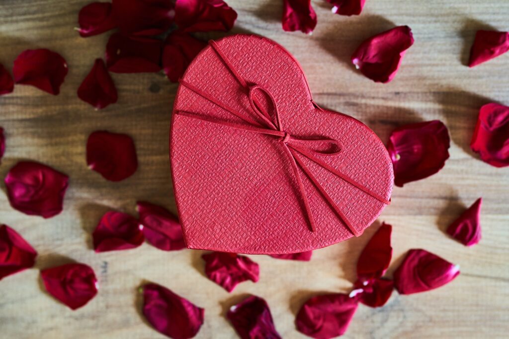 Rose petals surrounding heart-shaped gift box