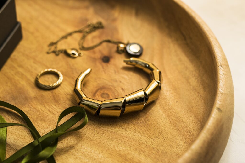 Gold ring, necklace, and bracelet on a wooden surface