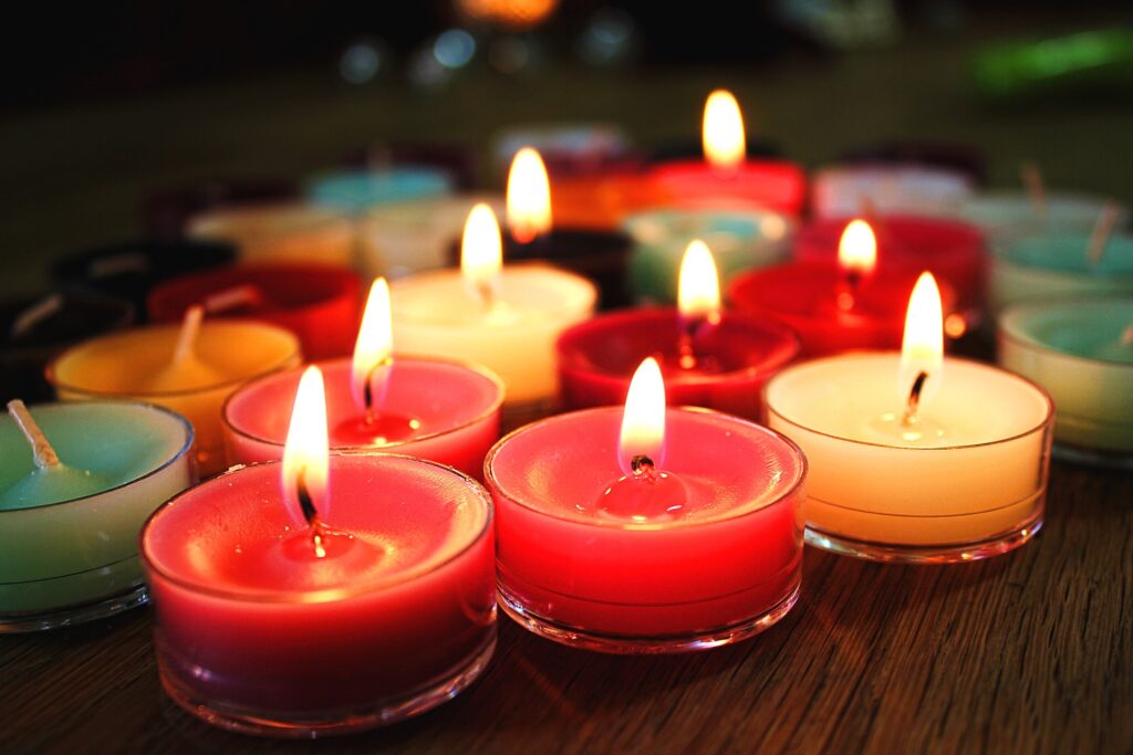 Close-up of lit, colorful tea lights on wooden surface