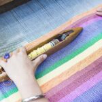 Person weaving colorful garment the old-fashioned way