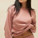 Model wearing pink sweatsuit exposing midriff