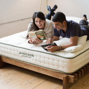 a picture of 2 people laying on an avocado mattress reading and laughing