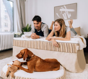 two people sitting on mattress with dog