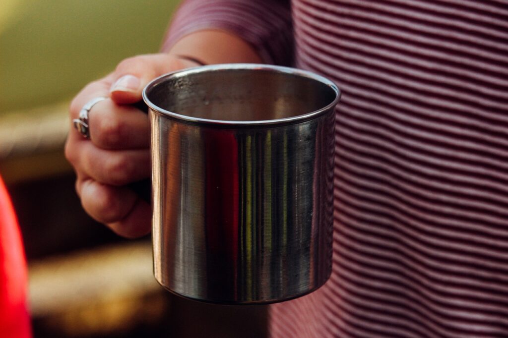 person holding a metal mug