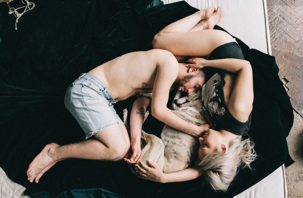 couple curled up on mattress with dog
